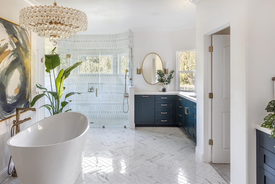 bright primary bathroom with blue cabinets and soaker tub
